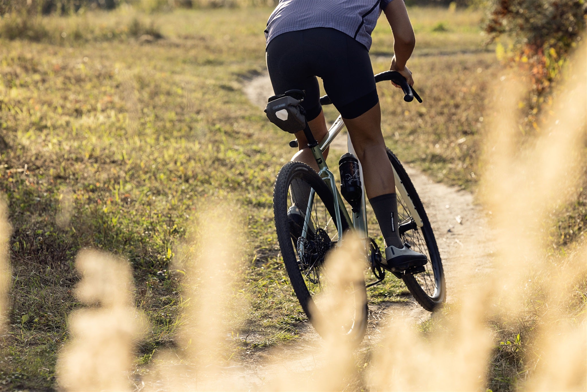 Radfahrer mit ORTLIEB Micro-Bag in dark-sand auf Schotterweg im Grünen